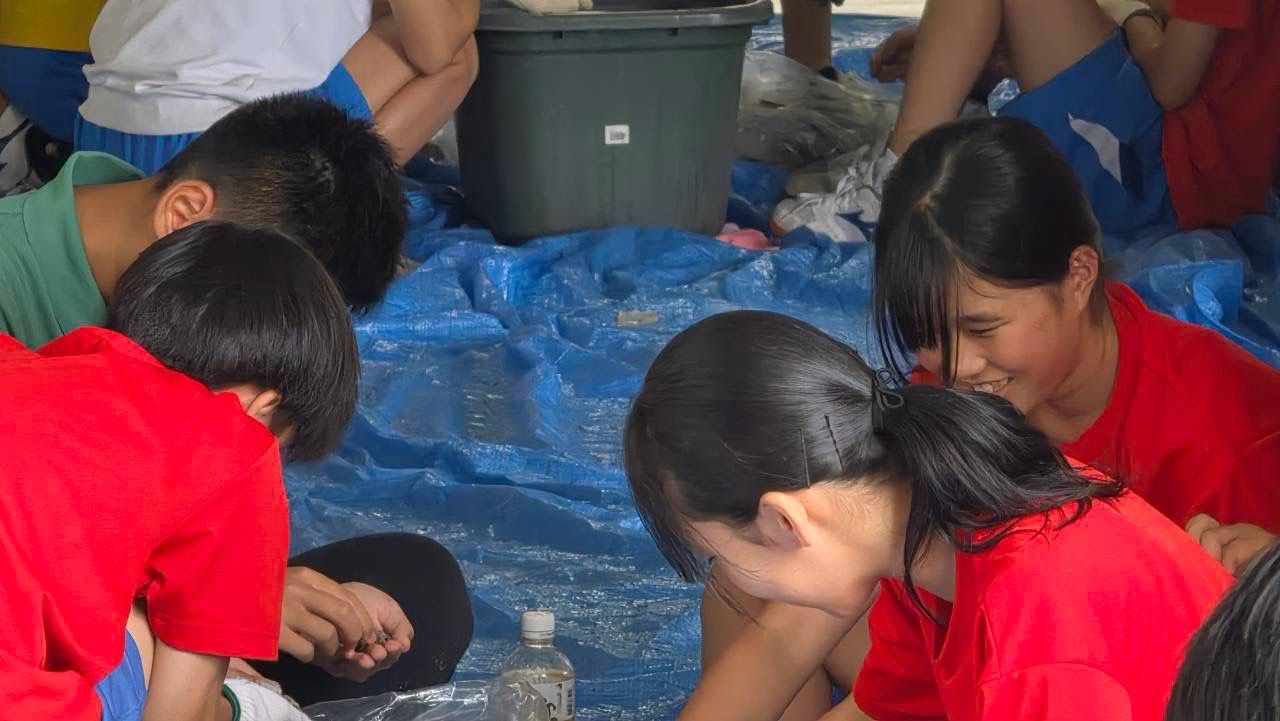 ブルーシートの上で笑いながら種を選り分ける子どもたち