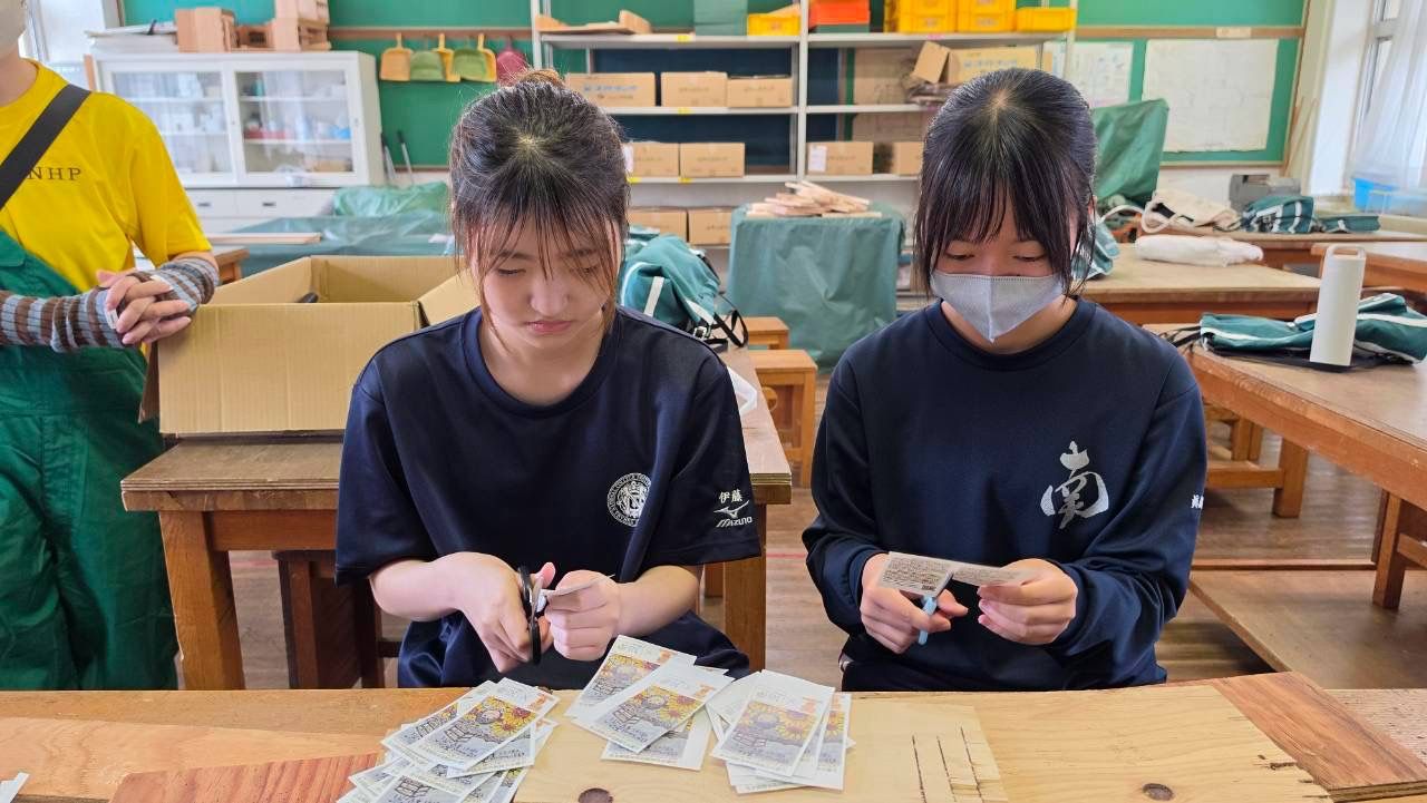 種の袋のラベルを切り分ける二人